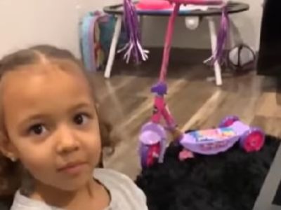 Rylee Butler is looking at the camera as there is her pink kick scooter in the background.